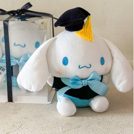 An officially licensed Sanrio Cinnamoroll plush toy dressed in a black graduation cap with a gold tassel and a matching gown featuring a large light blue bow