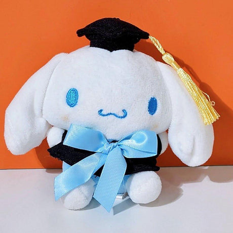 An officially licensed Sanrio Cinnamoroll plush toy dressed in a black graduation cap with a gold tassel and a matching gown featuring a large light blue bow