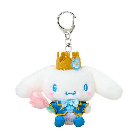 Sanrio Cinnamoroll plush keychain dressed as a prince in a blue and gold royal suit with a matching crown, holding a pink fabric tulip, attached to a silver metal lobster clasp.