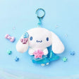 An officially licensed Sanrio character, Cinnamoroll features a shimmering metallic blue mermaid tail that replaces his traditional pup silhouette. The character is holding a pink starfish and has blue and pink shell accessories on its ear.