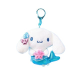 An officially licensed Sanrio character, Cinnamoroll features a shimmering metallic blue mermaid tail that replaces his traditional pup silhouette. The character is holding a pink starfish and has blue and pink shell accessories on its ear.