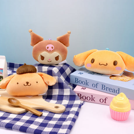 A collection of officially licensed Sanrio plush keychains featuring Kuromi, Cinnamoroll, and Pompompurin as bread buns in a golden-brown bread-like color, and matching plastic clips.