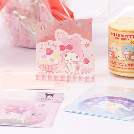 An officially licensed Class of 2026 Sanrio graduation gift set featuring six popular plush characters, Hello Kitty, My Melody, Cinnamoroll, Kuromi, Pompompurin, and Pochacco wearing black graduation caps. The characters are arranged like a bouquet with silver star balloons and "Congrats Grad" decorations.