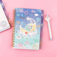 An officially licensed Sanrio Hangyodon spiral-bound notebook, featuring a glitter finish with gold stars and an illustration of Hangyodon. Includes four distinct, colorful dividers and five different interior page designs.