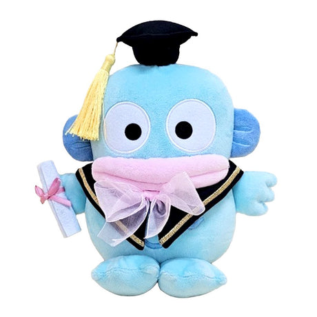 An officially licensed Sanrio 10-inch Hangyodon graduation plush sitting upright, wearing a black graduation cap with a yellow tassel and a pink bow around the neck while holding a white diploma