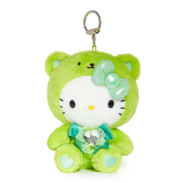 An officially licensed Sanrio Hello Kitty August birthstone plush keychain clip wearing a lime-green bear hood, a metallic pale green bow, and a teal ribbon with a heart-shaped faux gemstone.