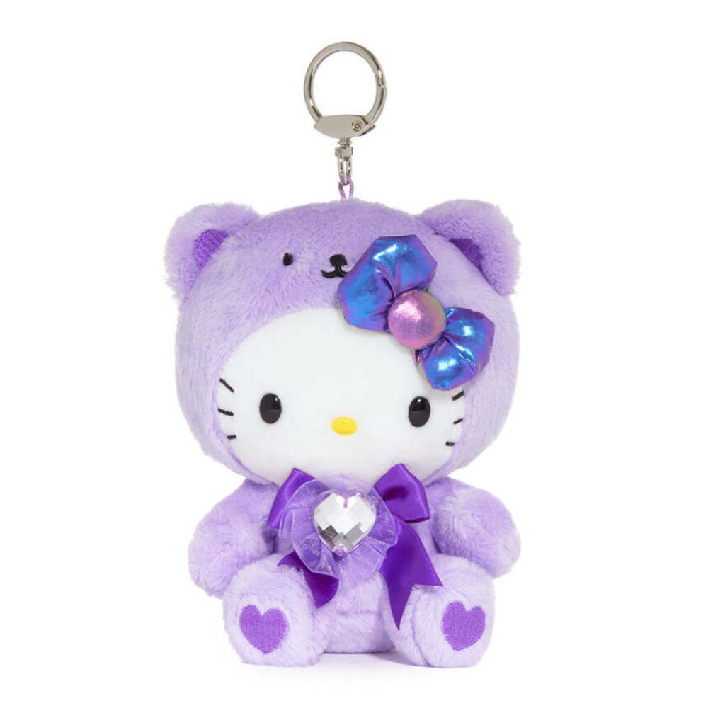 An officially licensed Sanrio Hello Kitty December birthstone plush keychain clip wearing a purple bear hood, a metallic blue-purple bow, and a dark purple ribbon with a heart-shaped faux gemstone.