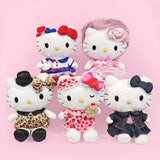 An officially licensed Sanrio collection of Hello Kitty plush dolls in various outfits, including a pink Lolita dress, leopard print dress with a top hat, strawberry-themed nightwear dress with a teddy bear, and a denim jacket ensemble.