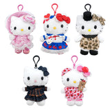 An officially licensed Sanrio collection of Hello Kitty plush keychains in various outfits, including a pink Lolita dress, leopard print dress with a top hat, strawberry-themed nightwear dress with a teddy bear, and a denim jacket ensemble. Each plush features a matching colored lobster clasp on top.