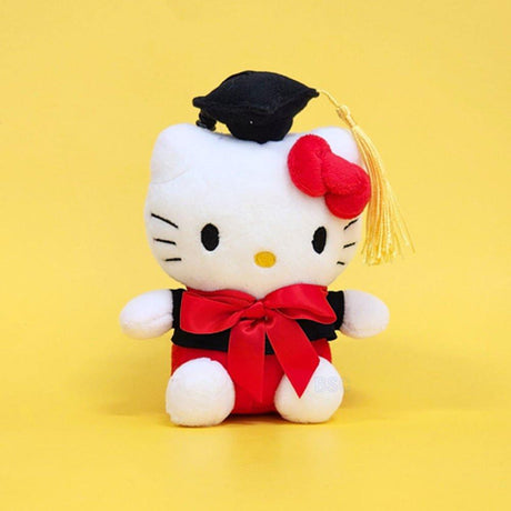 An officially licensed Sanrio Hello Kitty plush toy dressed in a black graduation cap with a gold tassel and a matching gown featuring a large red bow