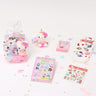 A collection of Sanrio Happy Birthday themed gift sets, each containing various colorful items such as plush keychains and socks, all packaged in clear gift bags with pink ribbons.