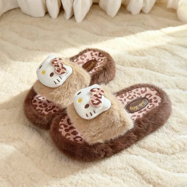 A pair of officially licensed Sanrio Hello Kitty plush slippers featuring brown and beige faux fur, a leopard print footbed, and 3D Hello Kitty face plush with matching leopard bows.