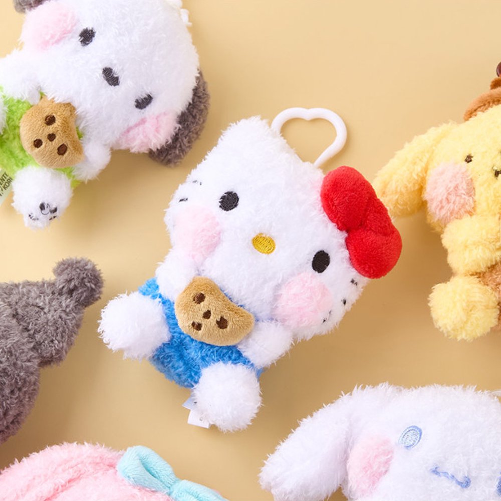 An officially licensed Sanrio collection of six shaggy-textured plush keychains including Hello Kitty, My Melody, Kuromi, Cinnamoroll, Pochacco, and Pompompurin, each holding a chocolate chip cookie. They are shown together with their respective heart-shaped clips.