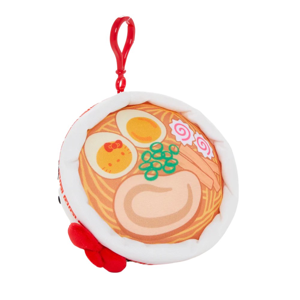 An officially licensed Sanrio plush keychain shaped like a white ramen bowl with Hello Kitty's face and a red bow. The top view shows a printed design of ramen noodles, green onions, and a Hello Kitty-themed egg.