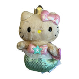 An officially licensed Sanrio Hello Kitty mermaid plush toy wearing a gold crown, a pink bow, and a green sequined mermaid tail with a starfish embellishment.
