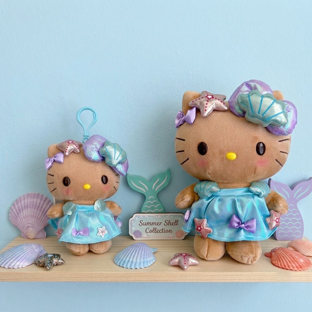 An officially licensed Sanrio collection of Hello Kitty plush toy and plush keychain with tan fur, dressed in a shimmering iridescent blue dress and an oversized metallic teal seashell headband.