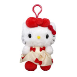 An officially licensed Hello Kitty plush keychain wearing a cream-colored satin dress decorated with small red bows. She has a big red plush bow on her head and a second smaller red bow on her other ear.