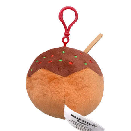 An officially licensed Sanrio plush keychain featuring Hello Kitty as a takoyaki ball with brown sauce, green sprinkles, and a small plush skewer. The round plush includes a red plastic attachment clip at the top.