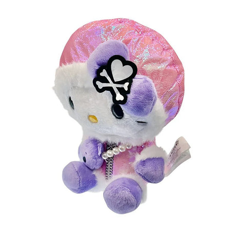  Hello Kitty x Tokidoki design is perfect for the holiday season. Hello Kitty sports a trendy look with an iridescent pink holographic beanie adorned with her signature purple bow decorated with a white heart and crossbones skull Tokidoki mark. She's dressed in a stylish pink holographic vinyl puffer jacket and holds an adorable purple bear plush with a pearl chain strap, giving her a fashionable streetwear vibe. Her soft plush body in white and purple creates the perfect bean doll silhouette for displaying