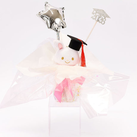 An officially licensed Class of 2026 Sanrio graduation gift set featuring six popular plush characters, Usahana, Corocorokuririn, Wish Me Mell, and Dinguri Days Mashu wearing black graduation caps. The characters are arranged like a bouquet with silver star balloons and "Congrats Grad" decorations.