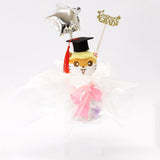 An officially licensed Class of 2026 Sanrio graduation gift set featuring six popular plush characters, Usahana, Corocorokuririn, Wish Me Mell, and Dinguri Days Mashu wearing black graduation caps. The characters are arranged like a bouquet with silver star balloons and "Congrats Grad" decorations.