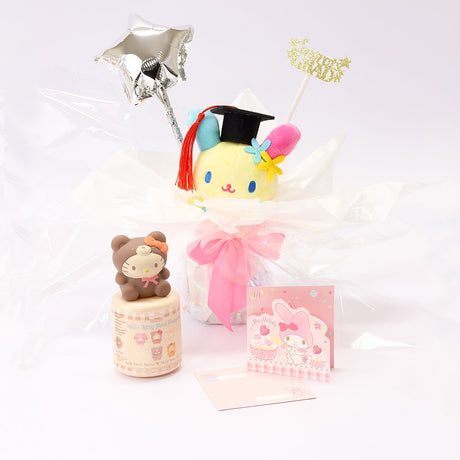 An officially licensed Class of 2026 Sanrio graduation gift set featuring six popular plush characters, Usahana, Corocorokuririn, Wish Me Mell, and Dinguri Days Mashu wearing black graduation caps. The characters are arranged like a bouquet with silver star balloons and "Congrats Grad" decorations.