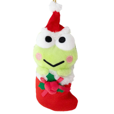 Sanrio Keroppi is dressed for the season wearing a red Santa hat with a white pom-pom while sporting his signature red bow. He sits snugly in a red Christmas stocking adorned with green holly leaves and a decorative ribbon. Crafted from soft plush material, this ornament has a cozy, huggable feel. The attached gold cord loop makes it easy to hang on your Christmas tree.