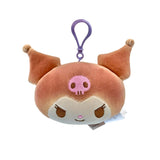 An officially licensed Sanrio plush keychain featuring Kuromi in a golden-brown bread-inspired color. The plush has a pink skull on its forehead, brown embroidered eyes, and a purple plastic attachment clip.