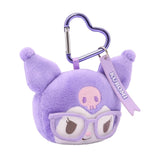 An officially licensed Sanrio Kuromi plush head keychain, wearing embroidered light purple glasses and a has a pink skull icon on her forehead. The keychain features a light purple, heart-shaped metal carabiner clip and a woven fabric tag that reads "KUROMI." The sturdy, heart-shaped carabiner in a matching metallic light purple finish, makes it easy to clip onto backpacks, purses, or belt loops.