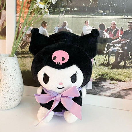 An officially licensed Sanrio Kuromi plush toy dressed in a black graduation cap with a gold tassel and a matching gown featuring a large light purple bow