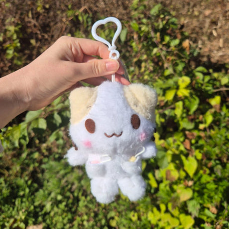 Officially licensed Sanrio character Mashumaro cat plush keychain with beige ears, pink blush, and tiny whiskers, featuring a white heart-shaped plastic clip.