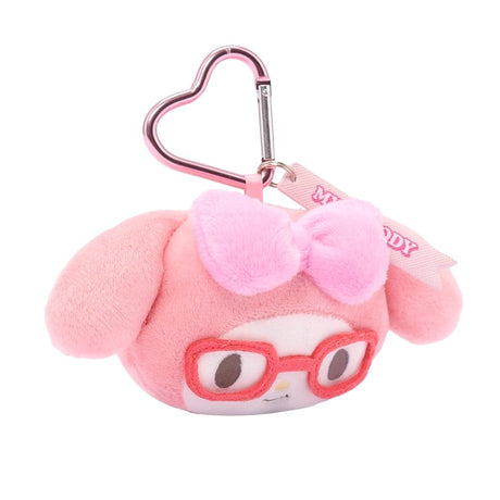 An officially licensed Sanrio My Melody plush head keychain, wearing embroidered red glasses and a textured pink bow. The keychain features a pink, heart-shaped metal carabiner clip and a woven fabric tag that reads "MY MELODY." The sturdy, heart-shaped carabiner in a matching metallic pink finish, makes it easy to clip onto backpacks, purses, or belt loops.