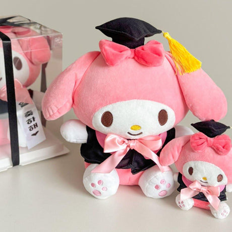 An officially licensed Sanrio My Melody plush toy dressed in a black graduation cap with a gold tassel and a matching gown featuring a large pink bow