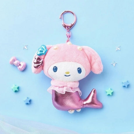 An officially licensed Sanrio character, My Melody mermaid plush keychain featuring a metallic pink tail, pink hood, and small shell accessories on her ear. She has a sheer pink ruffle around her waist and a pink plastic clip.