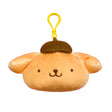 An officially licensed Sanrio plush keychain featuring Pompompurin in a golden-brown bread color. The plush includes his signature brown beret and a matching yellow plastic clip attached to the top.