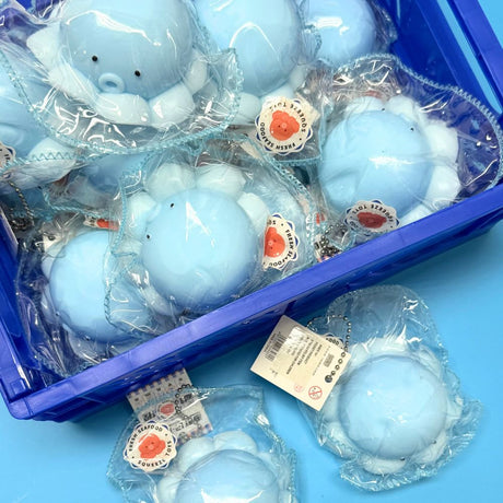 A crate filled with bulk Light Blue Octopus Mochi Squishy Toy Keychains with silver ball chains. Each cute sea animal squishy is individually wrapped with official product tags, making it ideal as party favors, backpack clips, and funny office fidget gifts.