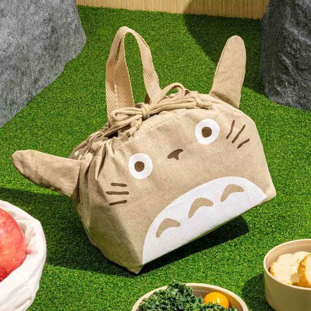 Officially licensed My Neighbor Totoro die-cut drawstring lunch pouch featuring 3D ears, Totoro's face, a drawstring tie, and top handles on natural beige fabric
