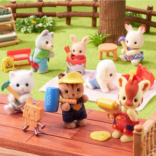 A collection of eight officially licensed Sylvanian Families baby figures in DIY themes, including a cat with a hammer, a giraffe with a paint roller, and a rabbit in a paint bucket. A pink question mark silhouette represents the eighth mystery figure in the series.