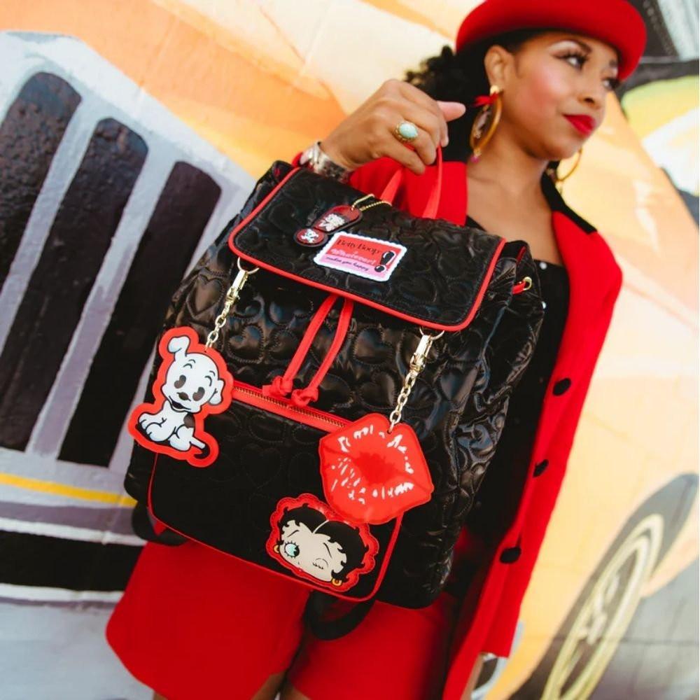 Black quilted heart-pattern backpack featuring Betty Boop and Pudgy character patches, vibrant red trim, and decorative gold chain charms shaped like red lips and Pudgy the dog.