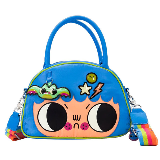An officially licensed Whatever! blue dome-shaped handbag featuring a large character face with giant black eyes and pink cheeks. The bag is decorated with a green bat-winged patch, a star, and a lightning bolt. It includes blue top handles and a detachable rainbow-striped shoulder strap.