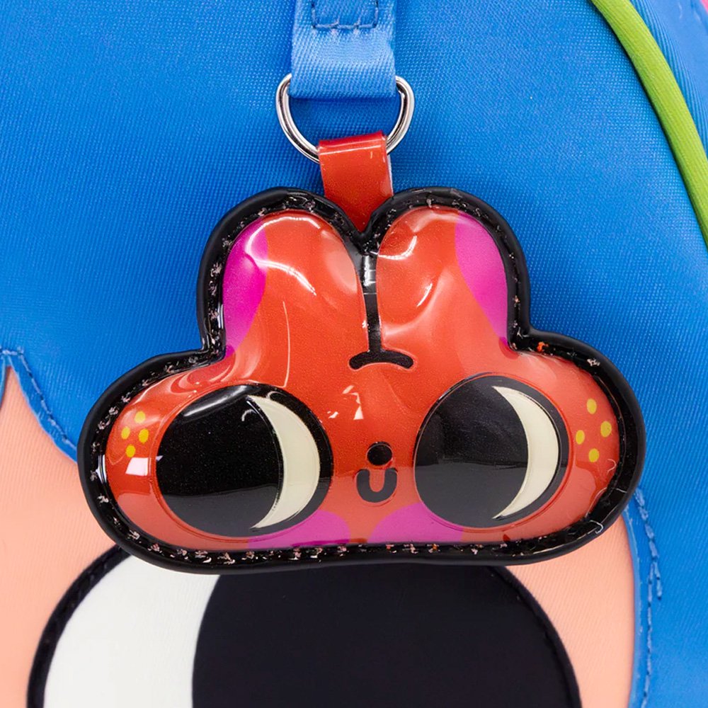 An officially licensed Whatever! blue dome-shaped handbag featuring a large character face with giant black eyes and pink cheeks. The bag is decorated with a green bat-winged patch, a star, and a lightning bolt. It includes blue top handles and a detachable rainbow-striped shoulder strap.