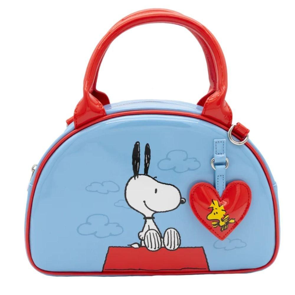 A light blue dome-shaped Snoopy crossbody bowler bag featuring Snoopy sitting on his red doghouse against a cloudy sky, with red handles, a striped rainbow shoulder strap, and a red heart-shaped Woodstock charm.