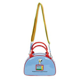 A light blue dome-shaped Snoopy crossbody bowler bag featuring Snoopy sitting on his red doghouse against a cloudy sky, with red handles, a striped rainbow shoulder strap, and a red heart-shaped Woodstock charm.
