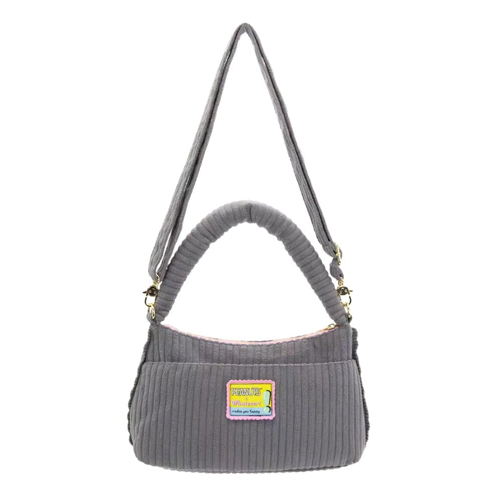 A grey corduroy shoulder bag decorated with an assortment of colorful Peanuts character buttons and floral patches