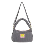 A grey corduroy shoulder bag decorated with an assortment of colorful Peanuts character buttons and floral patches