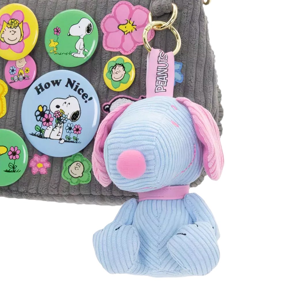 Six colorful, mini corduroy Snoopy plush charms in various pastel hues arranged around a pink mystery box