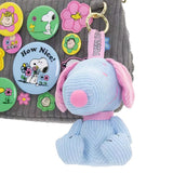 Six colorful, mini corduroy Snoopy plush charms in various pastel hues arranged around a pink mystery box