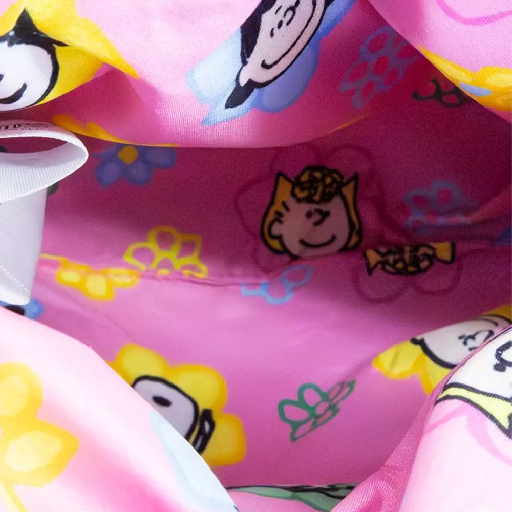 A pink corduroy plush bag shaped like Snoopy with floppy black ears, featuring a small top handle, a detachable pink shoulder strap, and a colorful yellow and blue "PEANUTS" patch on the side