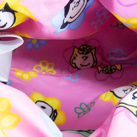A pink corduroy plush bag shaped like Snoopy with floppy black ears, featuring a small top handle, a detachable pink shoulder strap, and a colorful yellow and blue "PEANUTS" patch on the side