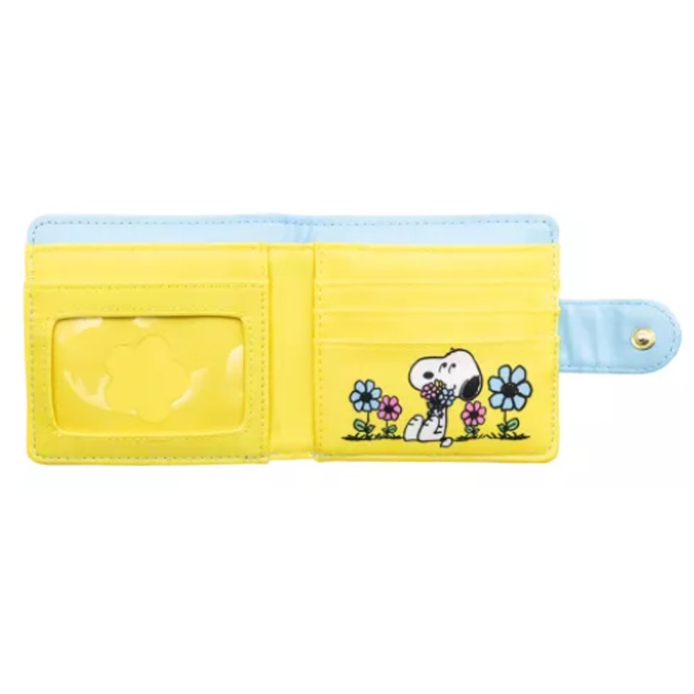 A light blue bi-fold wallet featuring Snoopy and Woodstock relaxing among colorful flowers, shown next to its open view displaying a bright yellow interior with card slots and a clear ID window.